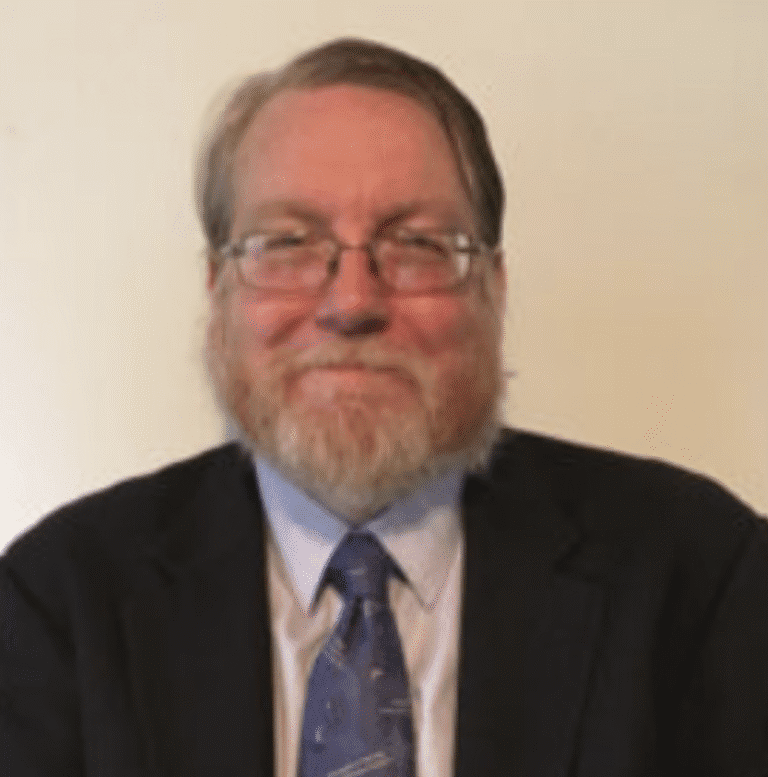 A man with glasses and a beard in a suit and tie.